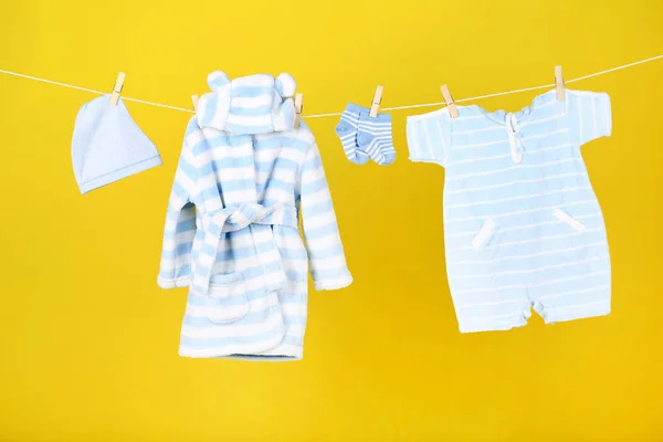 Ropa de bebé colgada sobre fondo amarillo —  Fotos de Stock