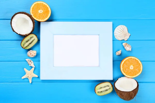 青いテーブルの上に貝殻と果物と木製の空白のフレーム — ストック写真