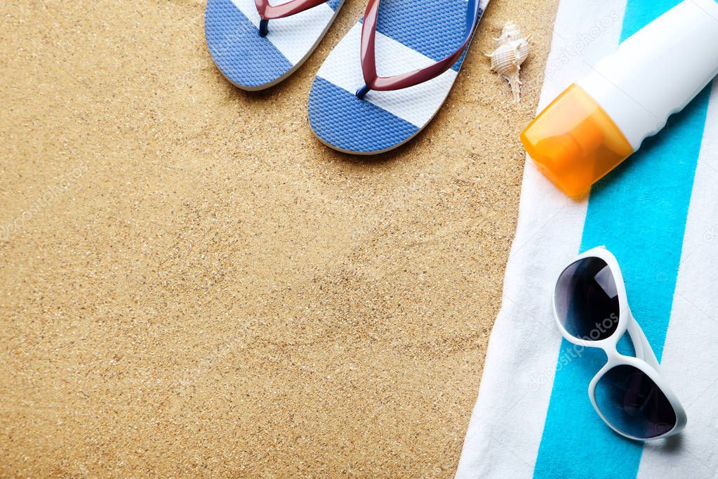 Flip flops with conch, sunglasses and moisturizer cream on beach