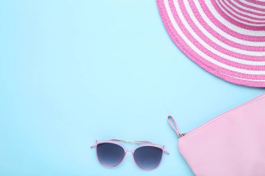 Mavi arka plan üzerinde çanta ve güneş gözlüğü ile Plaj şapkası