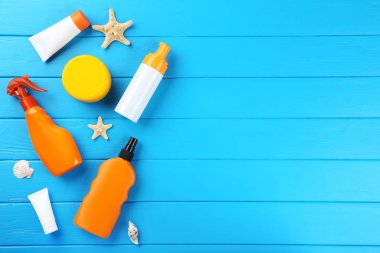 Mavi ahşap masa üzerinde deniz kabukları ile güneş kremi şişeleri