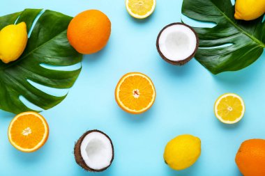 Mavi arka plan üzerinde yeşil monstera yaprakları ile farklı meyve