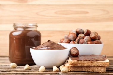 Kahverengi wo üzerinde eritilmiş çikolata, cam kavanoz ve fındık ile Ekmek