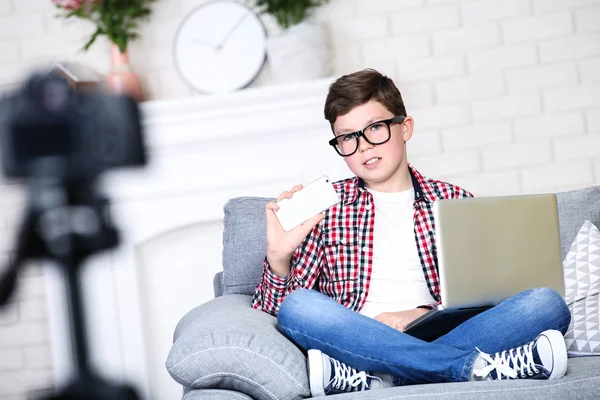 Молодий хлопець з ноутбуком сидить на дивані і записує відео — стокове фото