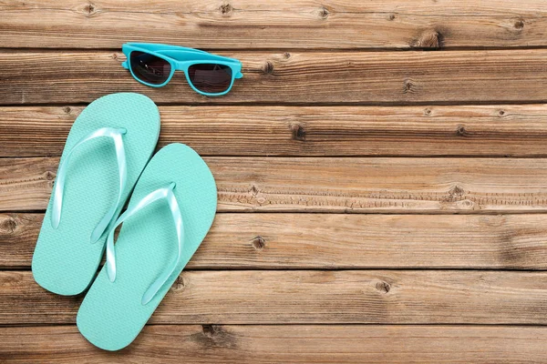 Pareja de chanclas con gafas de sol sobre mesa de madera marrón —  Fotos de Stock