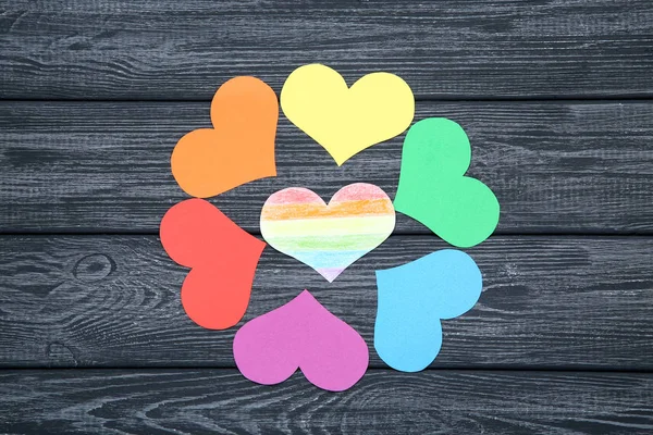 Corazones de papel arco iris sobre mesa de madera negra —  Fotos de Stock