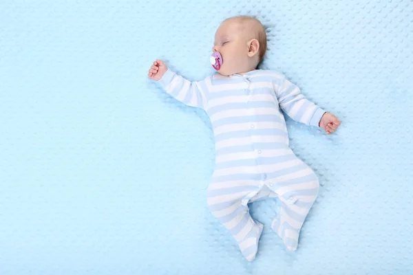 Menino com chupeta dormindo na cama azul — Fotografia de Stock