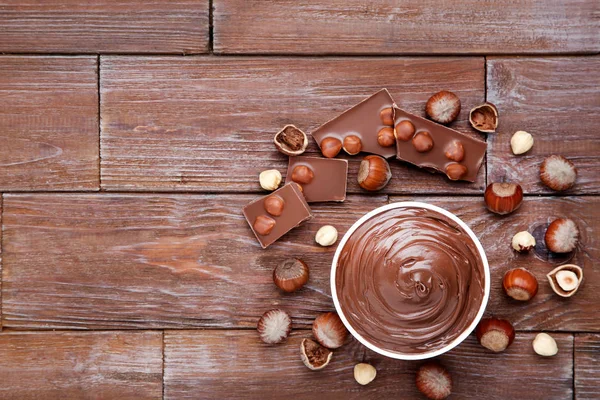 Chocolate derretido con avellanas sobre mesa de madera marrón —  Fotos de Stock