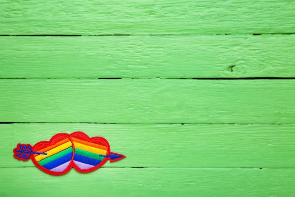 Corazones de arco iris con flecha sobre mesa de madera verde — Foto de Stock