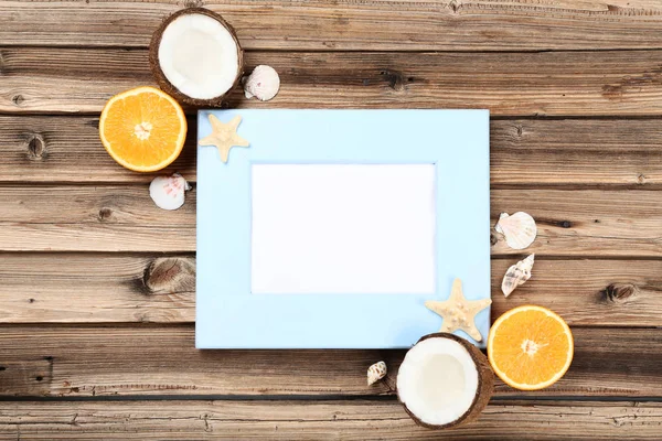 Wooden blank frame with seashells and fruits on brown table — Stock Photo, Image