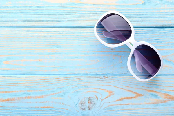 Nowoczesne okulary przeciwsłoneczne na niebieskim drewnianym stole — Zdjęcie stockowe