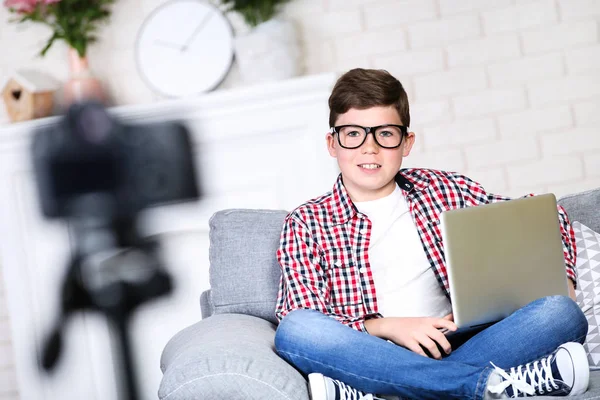 Jonge jongen met laptop zittend op Bank en records video — Stockfoto