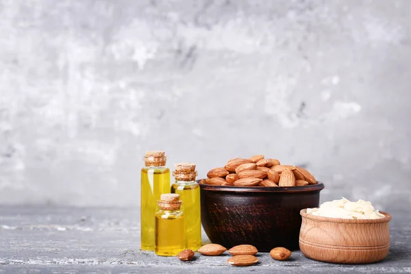 Amande et huile en bouteilles sur table en bois gris — Photo