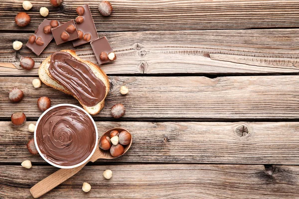 Pan con chocolate derretido y avellanas sobre mesa de madera marrón —  Fotos de Stock