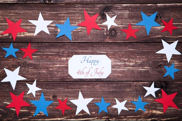 Texto Feliz 4 de julio con estrellas de papel sobre mesa de madera marrón — Foto de Stock