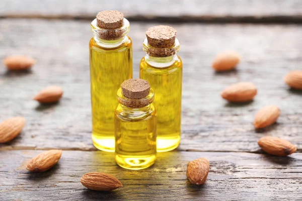 Almond and oil in bottles on grey wooden table — Stock Photo, Image