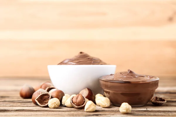 Melted chocolate with hazelnuts on brown wooden table — Stock Photo, Image