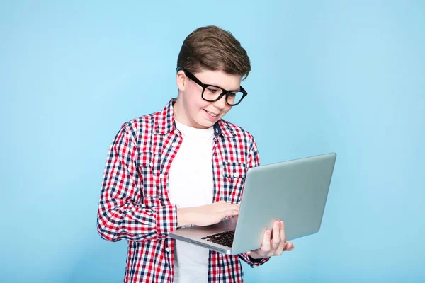 Молодий хлопчик тримає ноутбук на синьому фоні — стокове фото