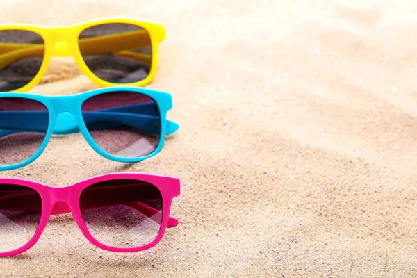 Coloridas gafas de sol en la arena de la playa — Foto de Stock