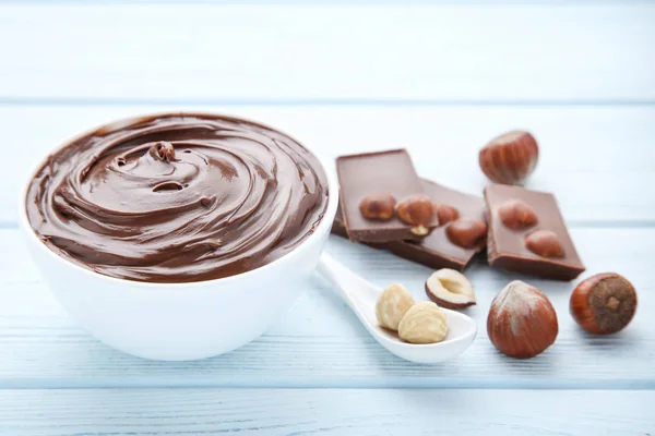 Melted chocolate with hazelnuts on wooden table — Stock Photo, Image