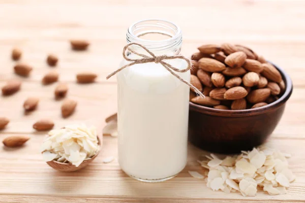 Almendra y leche en botella sobre mesa de madera marrón — Foto de Stock