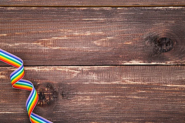 Rainbow ribbon on brown wooden table — Stock Photo, Image