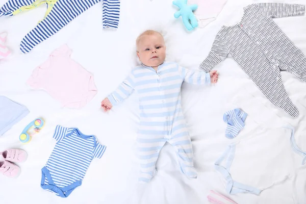 Малыш в модной одежде лежит на белой кровати — стоковое фото