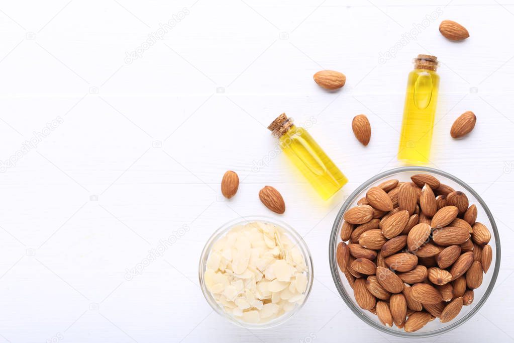 Almond and oil in bottles on white wooden table