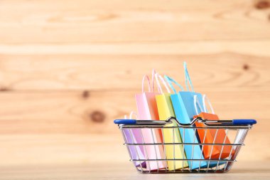 Kahverengi ahşap masa üzerinde alışveriş çantaları ile küçük metal sepeti