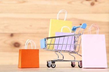 Kahverengi ahşap masa üzerinde alışveriş çantaları ile küçük metal sepeti