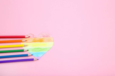Pembe arka plan üzerinde renkli kalemler ile Gökkuşağı kağıt kalp