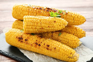 Tahta masada yeşil maydanozlu ızgara mısır.