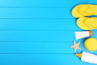 Denizyıldızı ve mavi ahşap ta üzerinde parmak arası terlik ile güneş kremi şişeleri