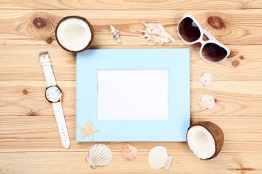 Tahta boş çerçeve, deniz kabukları, güneş gözlüğü ve hindistan cevizi.