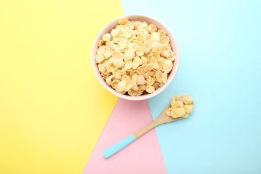 Renkli arka plan üzerinde kaşık ile kase mısır gevreği