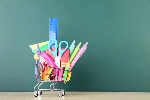 Schulbedarf mit Warenkorb auf Tafelhintergrund — Stockfoto