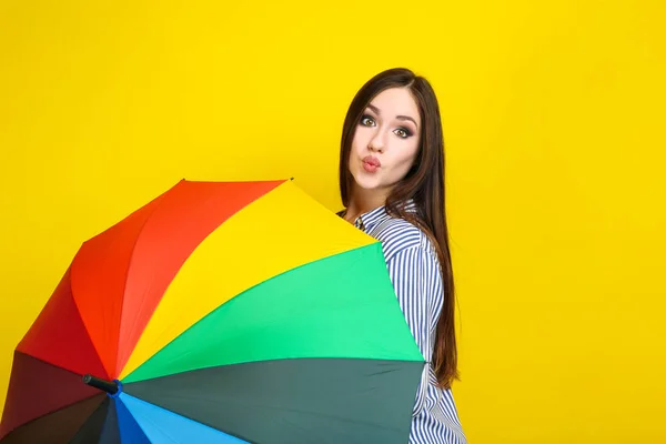 Young girl with colorful umbrella on yellow background — Stock Photo, Image