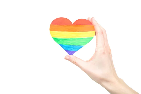 Mão feminina segurando coração de papel arco-íris no fundo branco — Fotografia de Stock