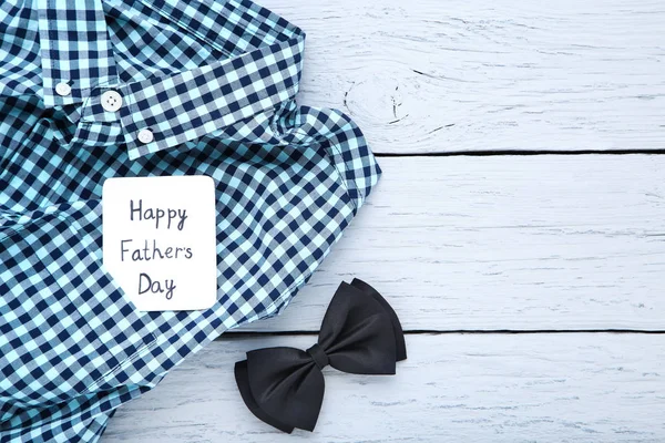 Text Happy Fathers Day with shirt and bow tie on wooden table