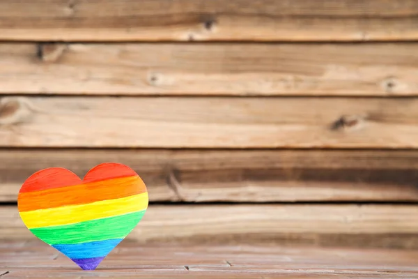 Herz aus Regenbogenpapier auf braunem Holztisch — Stockfoto