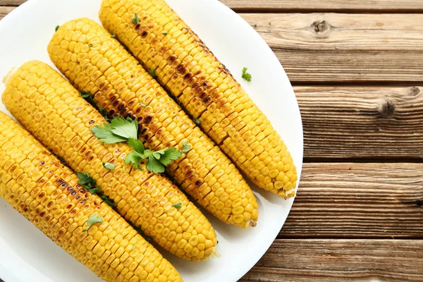 Grilled corn with green parsley on brown wooden table — Stock Photo, Image