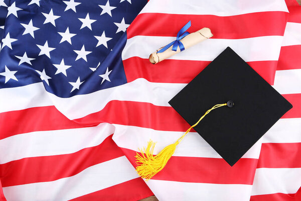 Graduation cap with diploma on American flag background