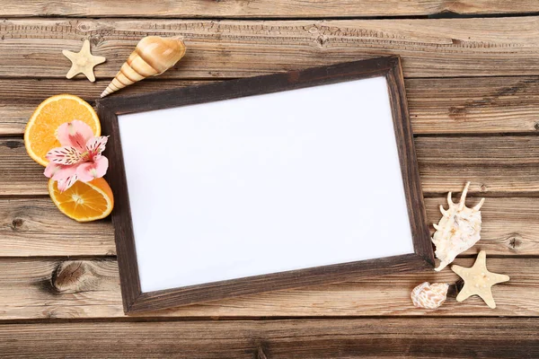 Wooden blank frame with seashells and orange fruits on brown tab — 스톡 사진