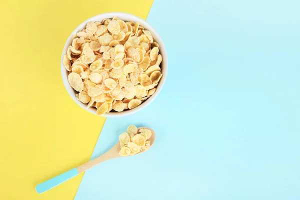 Corn flakes in bowl with spoon on colorful background — Stock Photo, Image