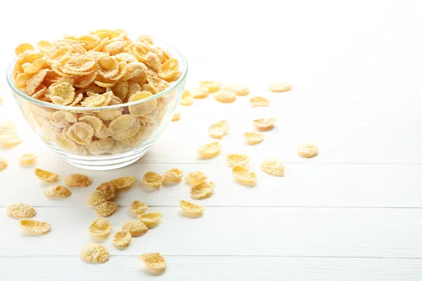 Corn flakes in glass bowl on white wooden table — Stock Photo, Image