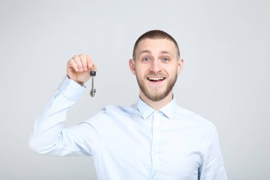 Young man with silver keys on grey background
