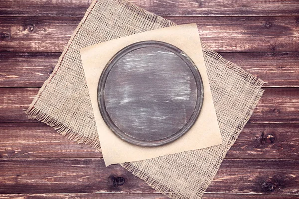 Dřevěné řezací prkno s žínkou na hnědém stole — Stock fotografie