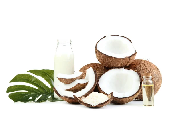Leche de coco en botella con aceite y hojas de monstera en la espalda blanca — Foto de Stock