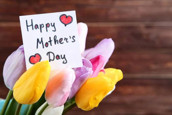 Bukiet kwiatów tulipana z tekstem szczęśliwy dzień matki na brązowym ba — Zdjęcie stockowe