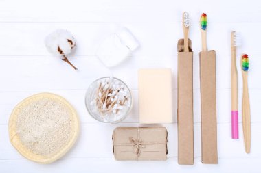 Beyaz ahşap masa üzerinde sabun, bez, pamuk çubukları ve diş ipi ile Bambu diş fırçaları